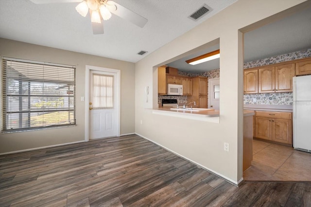 kitchen with dark wood-style floors, light countertops, white appliances, and visible vents