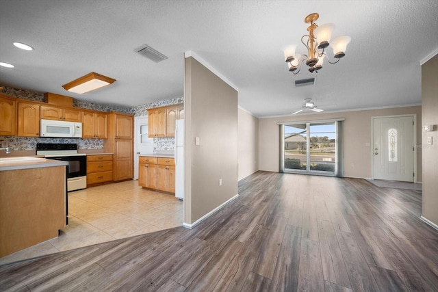 kitchen featuring white appliances, visible vents, open floor plan, ornamental molding, and backsplash