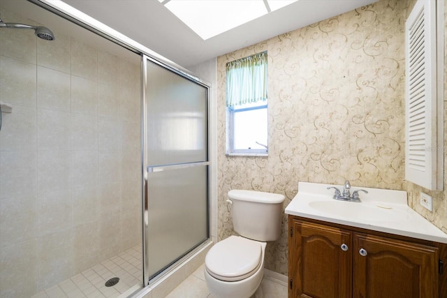 bathroom with vanity, a shower stall, toilet, and wallpapered walls