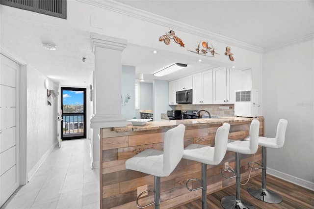 kitchen with black microwave, visible vents, ornamental molding, backsplash, and ornate columns