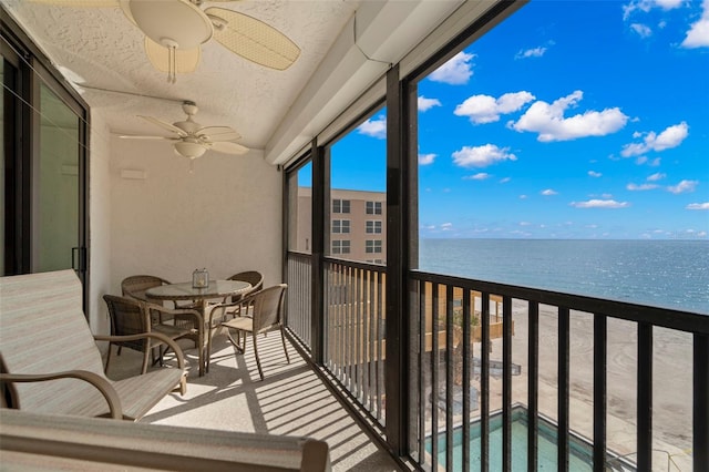 balcony featuring a water view and a ceiling fan