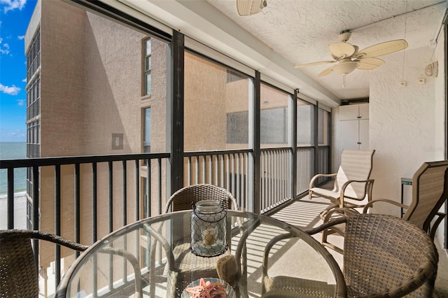 sunroom / solarium with a water view and a ceiling fan