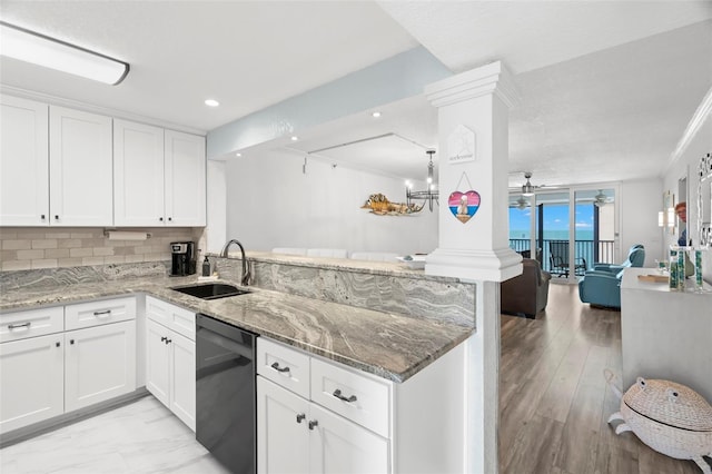 kitchen with a peninsula, a sink, open floor plan, dishwasher, and ornate columns