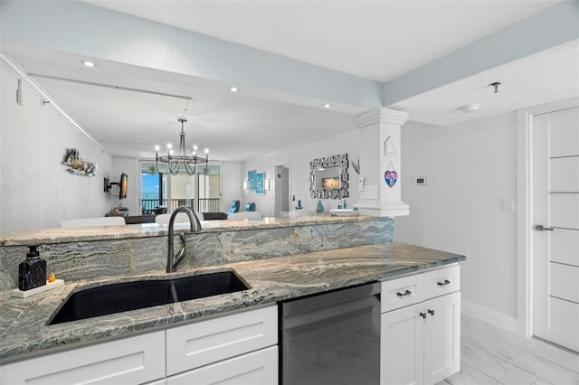 kitchen featuring marble finish floor, stainless steel dishwasher, white cabinets, a sink, and light stone countertops