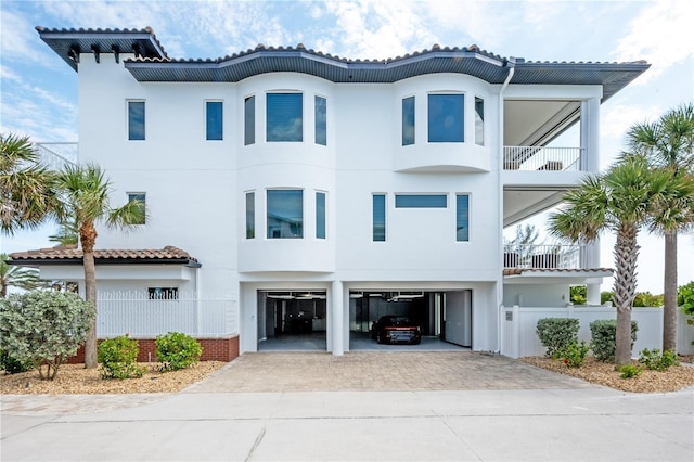 view of front of home featuring decorative driveway, a tiled roof, an attached garage, and stucco siding