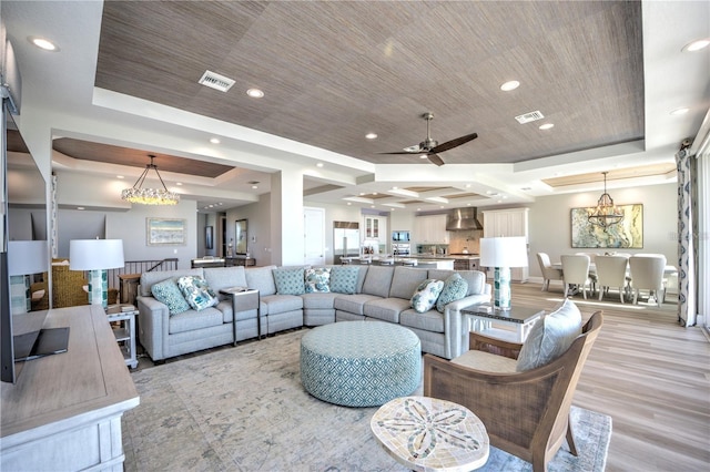 living area with a tray ceiling, visible vents, and recessed lighting