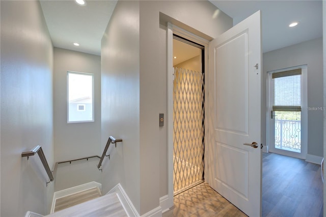 interior space with a healthy amount of sunlight, recessed lighting, wood finished floors, and an upstairs landing