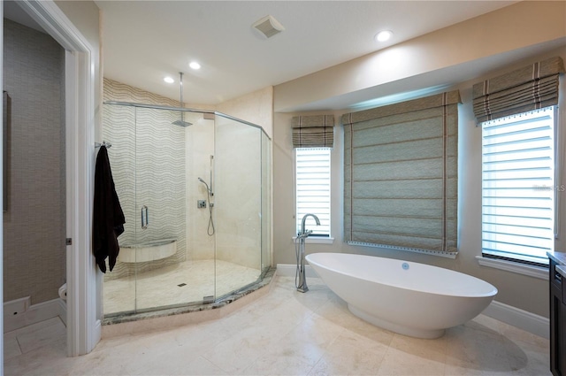 bathroom with a healthy amount of sunlight, a freestanding tub, a shower stall, and baseboards