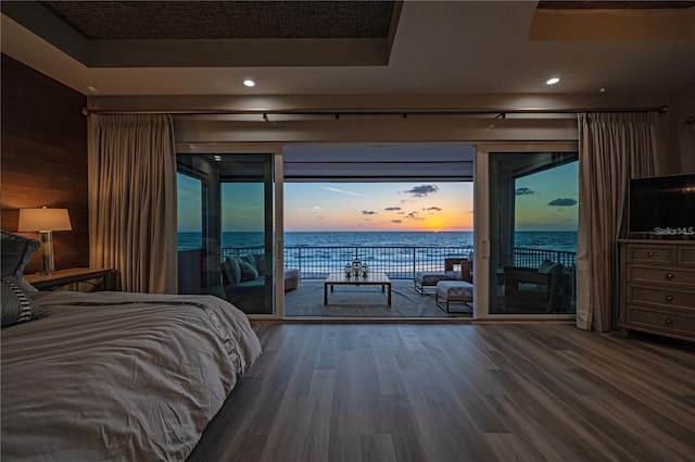 bedroom featuring access to exterior, recessed lighting, a raised ceiling, and wood finished floors