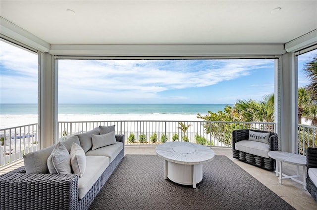 sunroom with a water view, a beach view, and a wealth of natural light