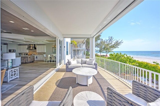 wooden terrace featuring a water view and a view of the beach