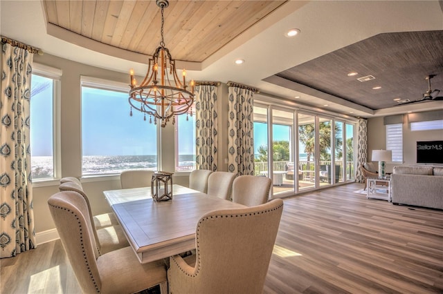 dining area with a raised ceiling, wooden ceiling, plenty of natural light, and wood finished floors