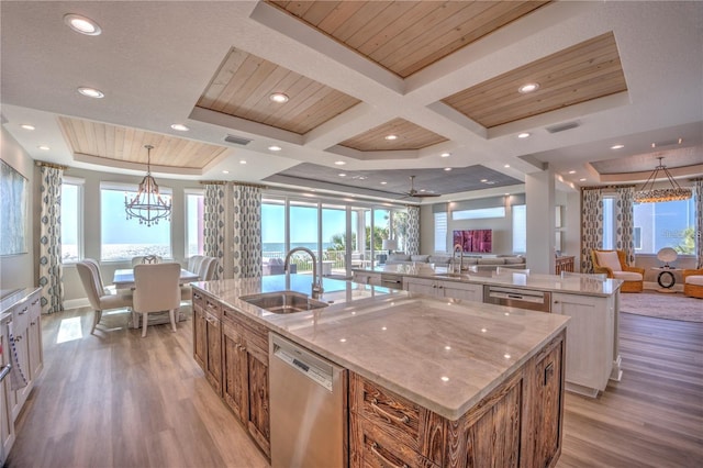 kitchen featuring a large island with sink, a sink, open floor plan, and stainless steel dishwasher