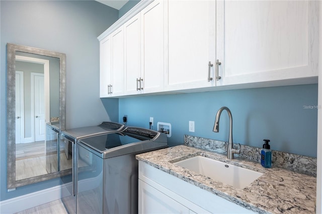 clothes washing area featuring cabinet space, a sink, and washer and clothes dryer