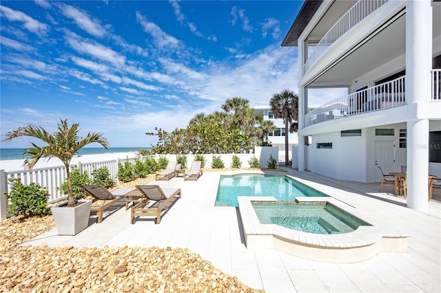 view of pool featuring a water view, a patio area, a fenced backyard, and a pool with connected hot tub