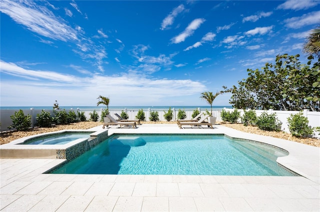 view of pool with a patio, a water view, fence, and a pool with connected hot tub