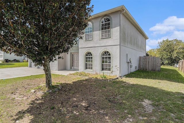 view of front of home with concrete driveway, an attached garage, fence, a front yard, and stucco siding