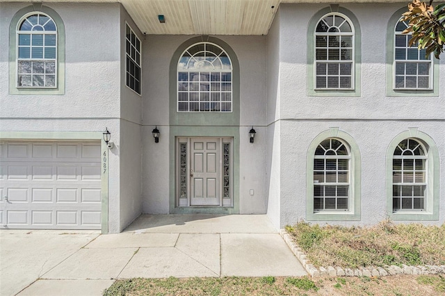 entrance to property featuring a garage and stucco siding