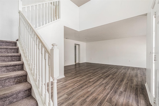 staircase with wood finished floors and a towering ceiling