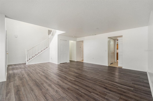 unfurnished living room featuring visible vents, stairway, a textured ceiling, wood finished floors, and baseboards