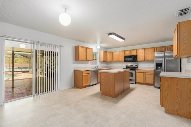 kitchen featuring appliances with stainless steel finishes, light countertops, visible vents, and a kitchen island