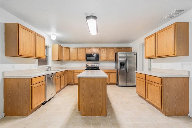 kitchen featuring a sink, visible vents, light countertops, appliances with stainless steel finishes, and a center island