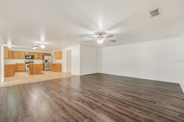 unfurnished living room featuring visible vents, ceiling fan, a textured ceiling, and wood finished floors