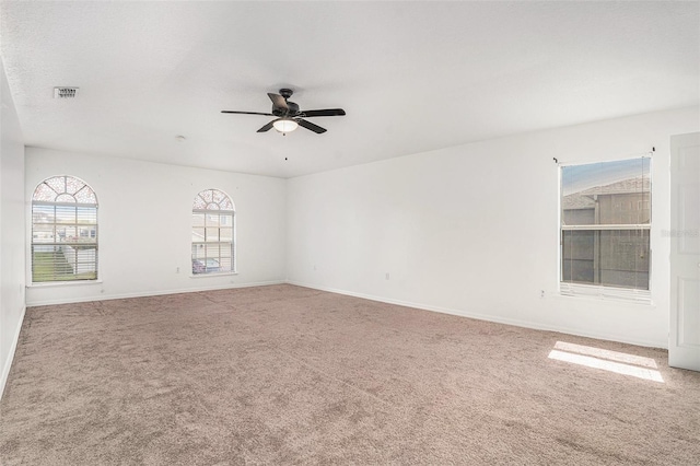 carpeted spare room with visible vents, ceiling fan, and baseboards