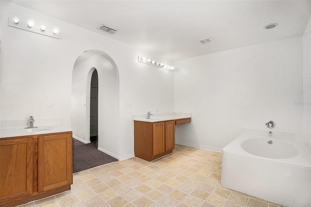 bathroom featuring a sink, a garden tub, two vanities, and visible vents