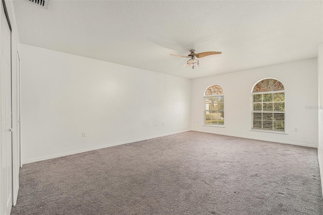 spare room featuring a textured ceiling, baseboards, a ceiling fan, and carpet flooring