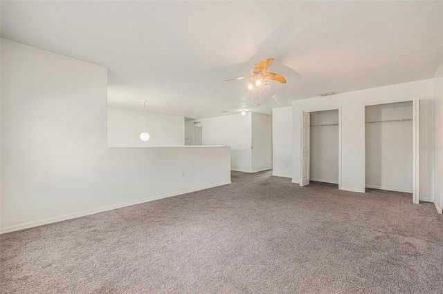 unfurnished bedroom with multiple closets, a ceiling fan, carpet flooring, a textured ceiling, and baseboards