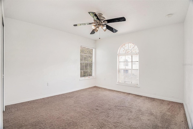 empty room featuring carpet floors, a ceiling fan, and baseboards