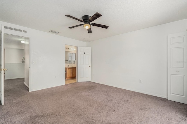 unfurnished bedroom with carpet, visible vents, a textured ceiling, and ensuite bath