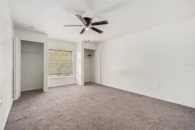 unfurnished bedroom featuring a textured ceiling, ceiling fan, carpet floors, baseboards, and multiple closets