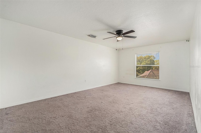 carpeted spare room featuring visible vents, ceiling fan, a textured ceiling, and baseboards