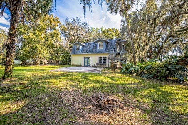 rear view of house with a yard, roof with shingles, and a patio