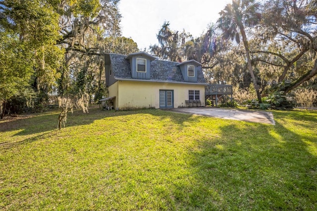 rear view of property featuring french doors, a yard, and stucco siding