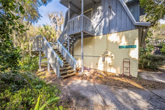 view of side of home with board and batten siding and stairs