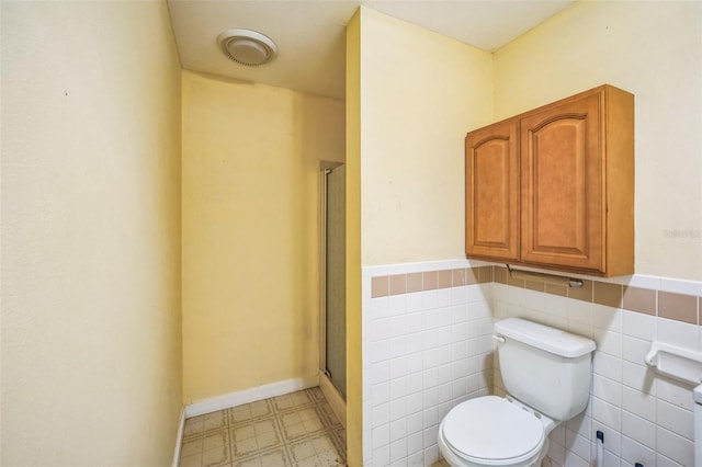 full bathroom featuring a stall shower, tile walls, toilet, and tile patterned floors