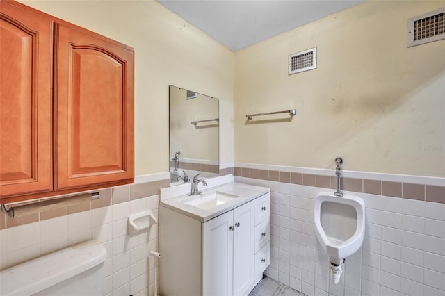 bathroom featuring visible vents, a wainscoted wall, toilet, and tile walls