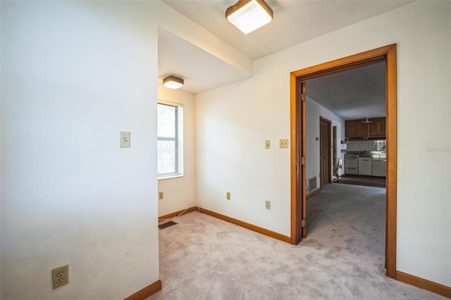 empty room with baseboards, visible vents, and light colored carpet