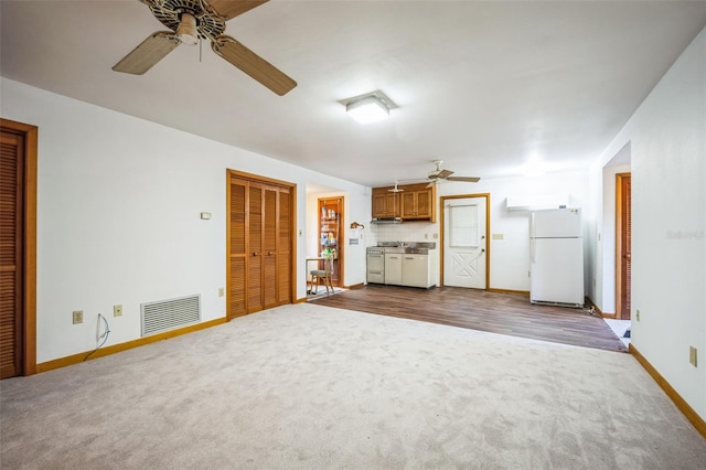 unfurnished living room featuring baseboards, visible vents, a ceiling fan, dark colored carpet, and separate washer and dryer