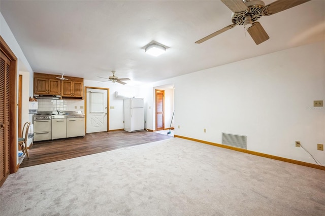 interior space featuring electric range, visible vents, freestanding refrigerator, dark carpet, and backsplash