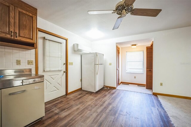 kitchen featuring dark wood-style floors, tasteful backsplash, stainless steel countertops, freestanding refrigerator, and baseboards