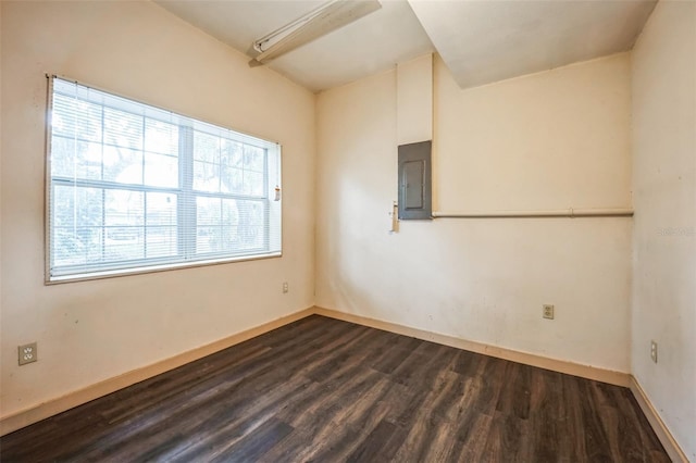 spare room featuring dark wood-style flooring, electric panel, and baseboards