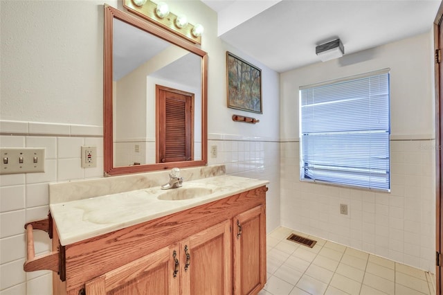 bathroom featuring visible vents, a wainscoted wall, tile patterned floors, vanity, and tile walls