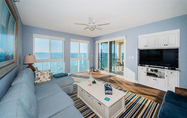 living room with ceiling fan, baseboards, and wood finished floors