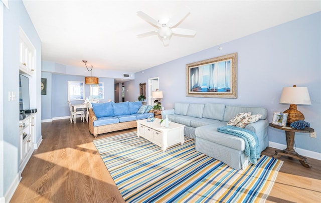 living room with a ceiling fan, baseboards, and wood finished floors