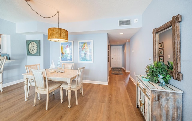 dining room with light wood finished floors, baseboards, visible vents, and recessed lighting