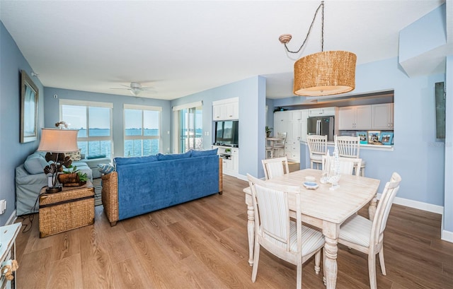 dining space featuring ceiling fan, light wood-type flooring, and baseboards